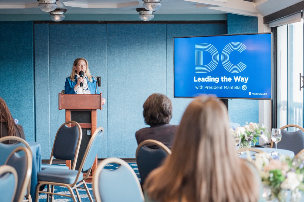 Woman speaks into microphone as she looks towards the door